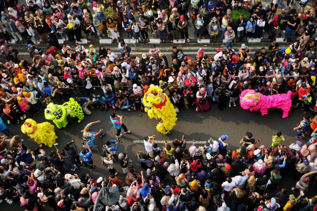 Aerial view of a colorful lion dance festival in Jawa Barat, Indonesia, with a large crowd celebrating.