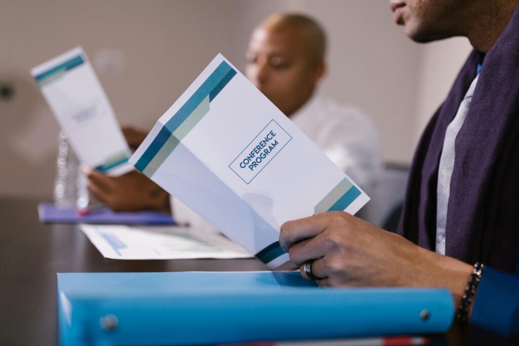 Close-up view of attendees reading conference programs during a business meeting.