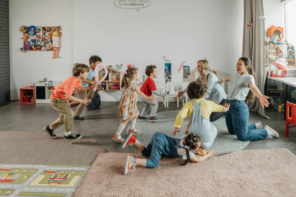 Joyful children and teachers playing together in a colorful classroom setting.