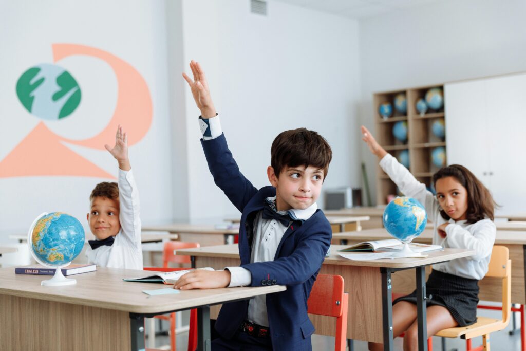 Students in a classroom eagerly raising their hands during a lesson.