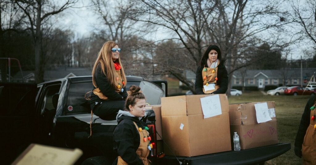 Volunteers in Christmas attire organizing gift delivery from a truck in a neighborhood.