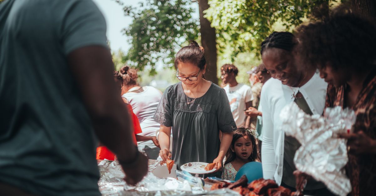 A lively barbecue gathering with diverse group outdoors enjoying food and summer weather.