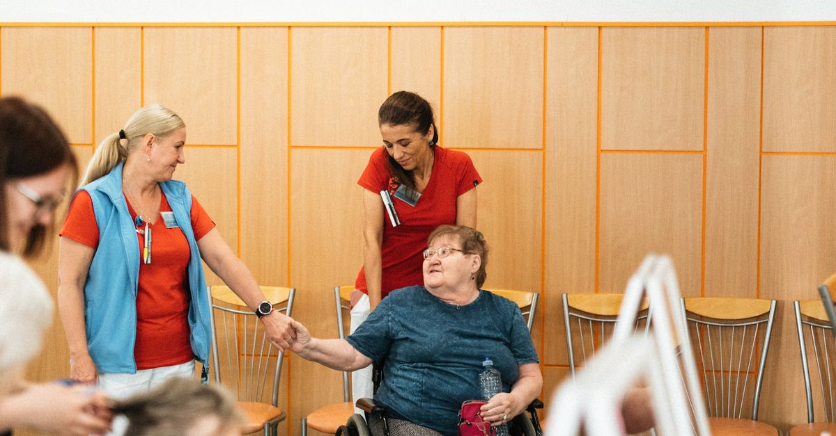 Healthcare professionals interact with elderly individuals in a care facility.