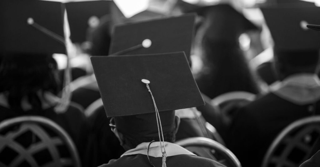 Black and white photograph of students wearing mortarboards at a graduation ceremony.