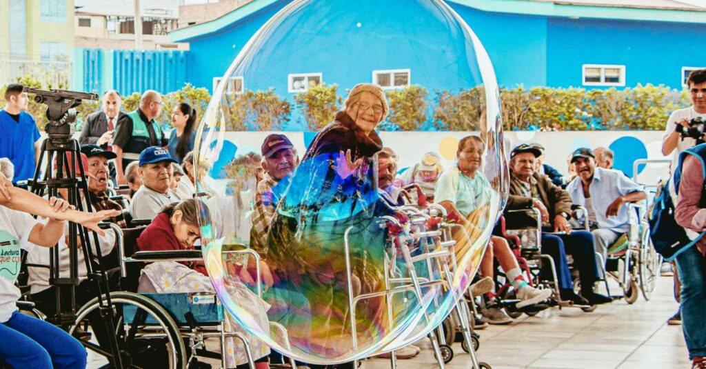 Elderly people enjoying a fun moment with a giant bubble outdoors in Lima, Peru.