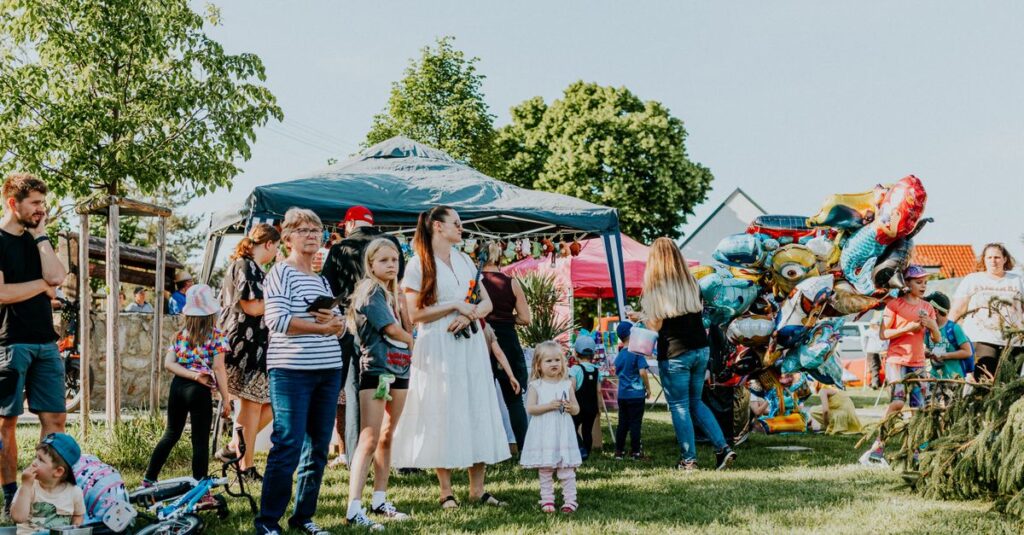 A lively outdoor gathering with families enjoying balloons and a sunny day.