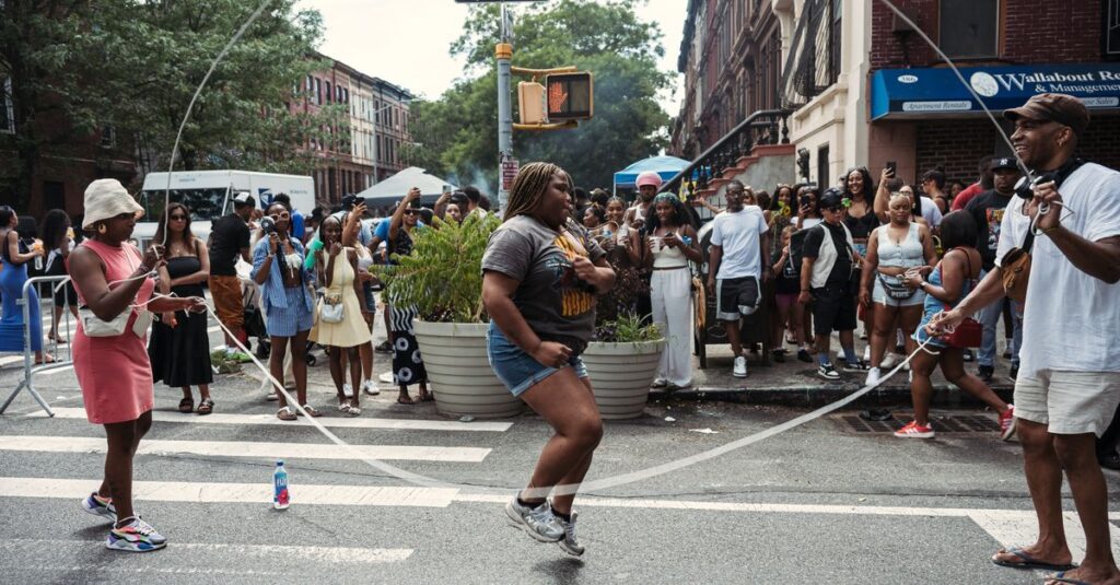 Joyful scene at a lively Brooklyn block party with people enjoying jump rope and street festivities.