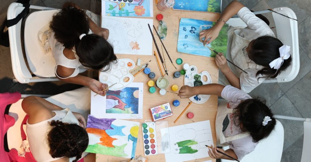 Children paint and draw in an art workshop, utilizing various colors and materials.