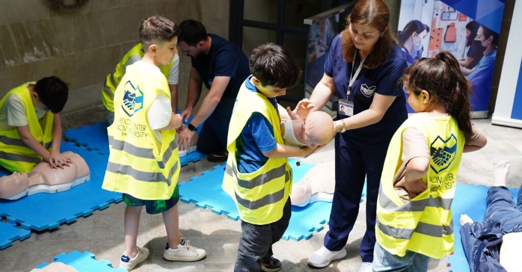 Kids learning CPR skills in an educational safety workshop indoors led by instructor.