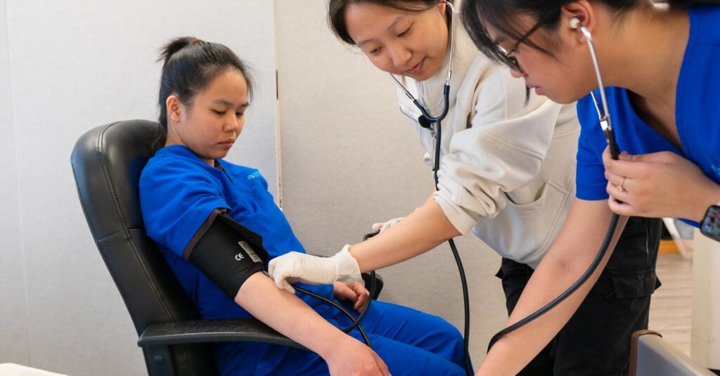 Healthcare professionals conducting a blood pressure check on a patient in a clinical setting.