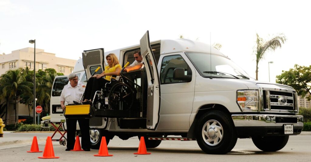 A wheelchair lift transfers a person into an accessible van on a sunny day.