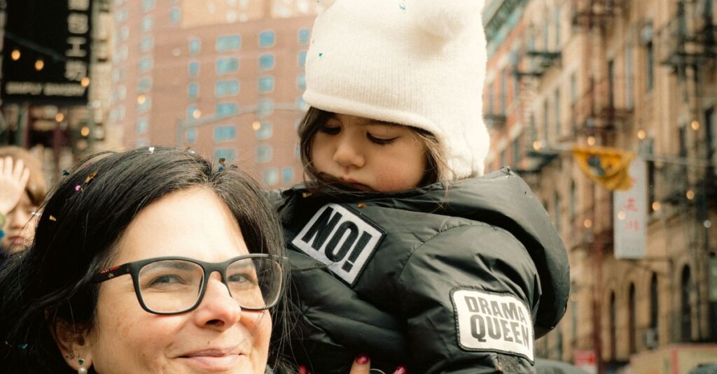 A mother and child embrace amidst a lively street parade in New York City.