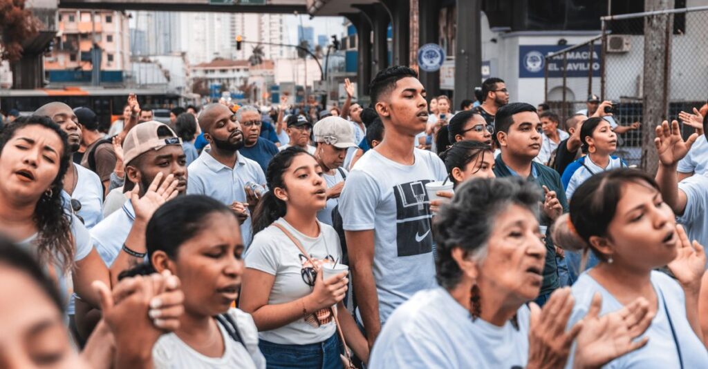 A large group of diverse people gathered outdoors, engaging in a community event in an urban setting.