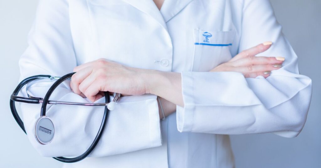 A close-up image of a doctor in a white coat with a stethoscope and arms crossed.