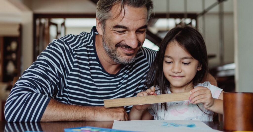 Father and daughter enjoying quality time painting and crafting indoors.