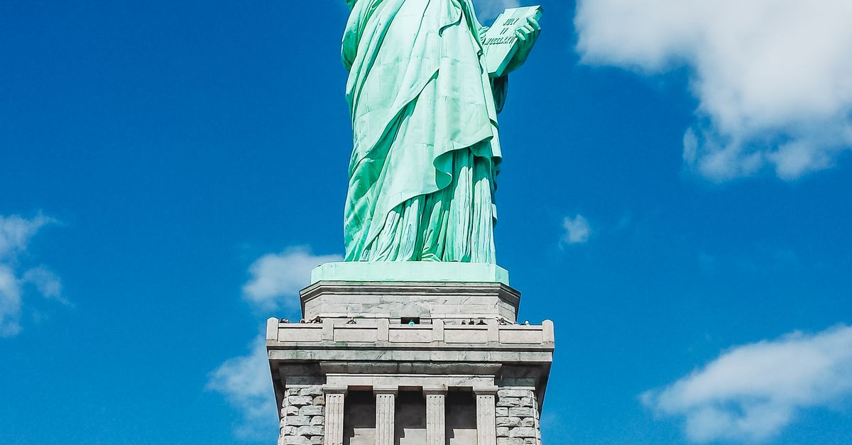 Iconic Statue of Liberty shot with a dramatic low angle against a clear blue sky, perfect for travel and tourism themes.