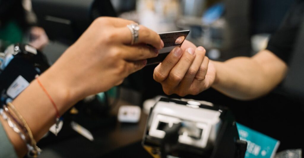 Close-up of hands completing a payment transaction at a retail checkout using a bank card.