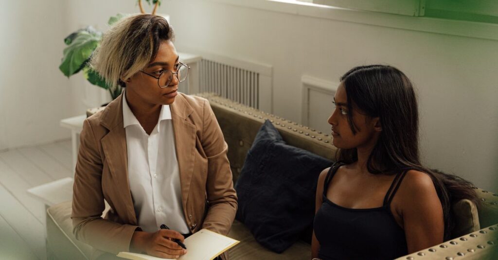 Two women engaged in a counseling session indoors, promoting dialogue and learning.