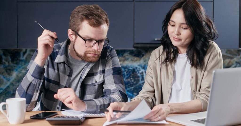 A couple is reviewing and calculating their household bills together at home.
