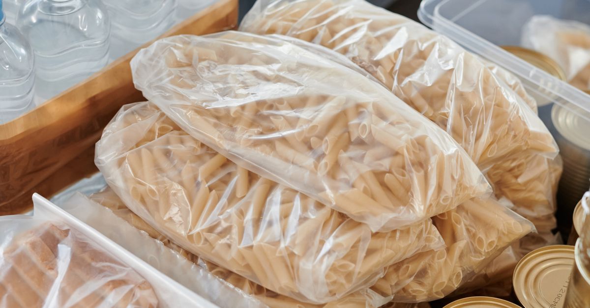 Packed groceries and canned food ready for donation. Includes pasta, water bottles, and bread.