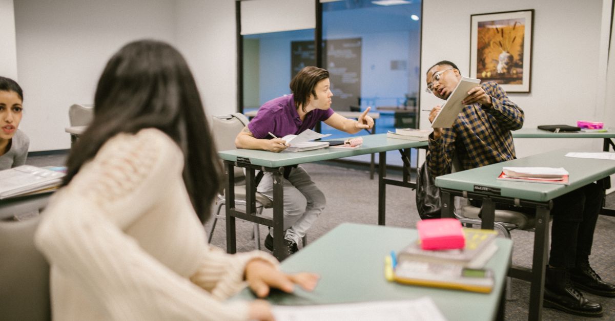 College students engaging in conversation during class, indicating collaboration and learning.