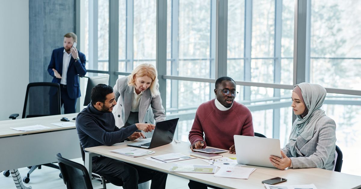 Multicultural group of professionals discussing ideas in a bright, modern office setting.