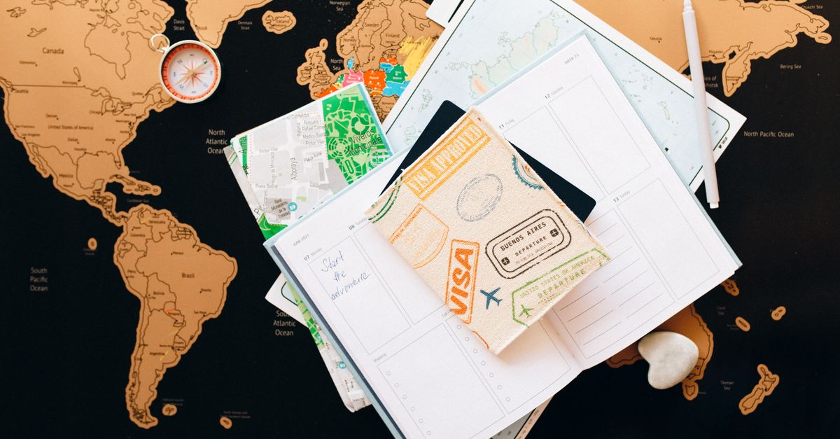 A flat lay of travel planning items on a map, featuring a compass, notebook, and guide for wanderlust enthusiasts.