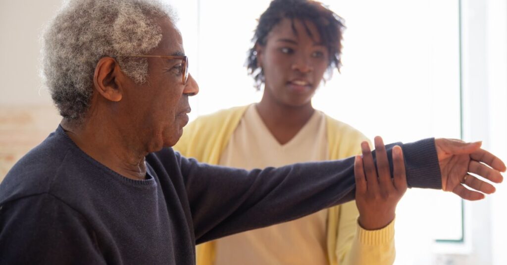 A caregiver helps an elderly man with arm exercises in a warm and caring environment.