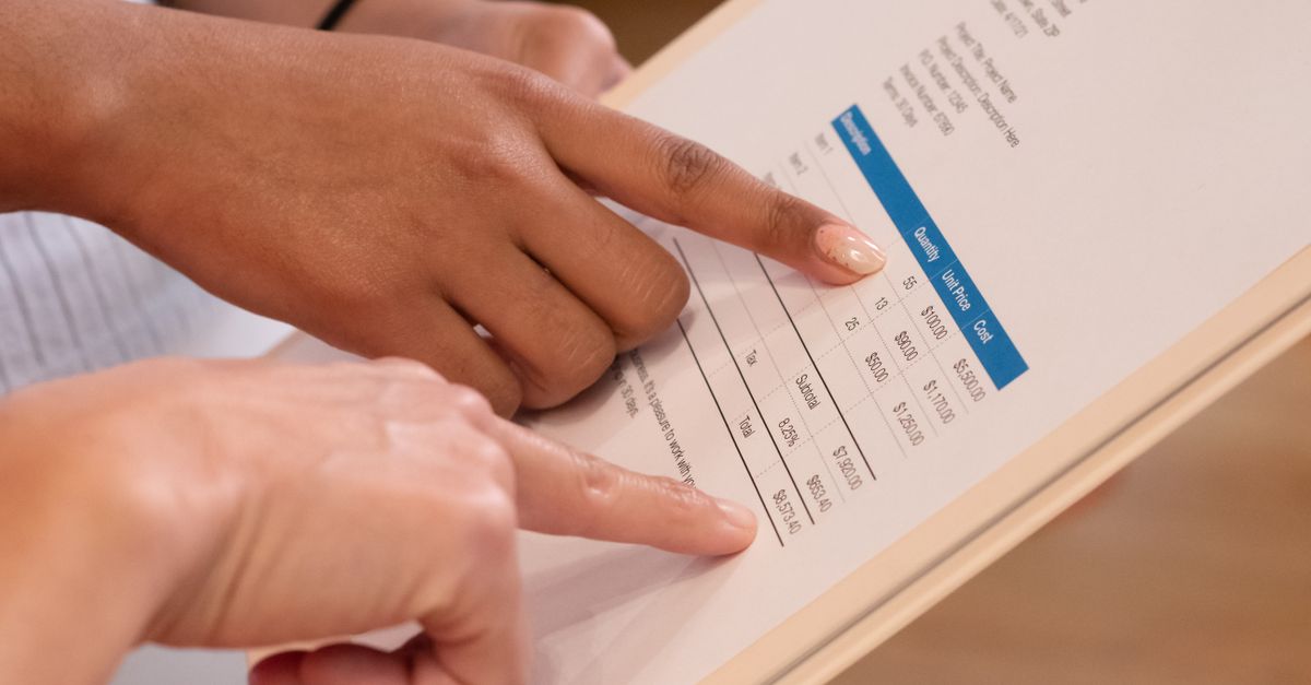 Two people pointing at financial details on a document, highlighting invoice analysis.