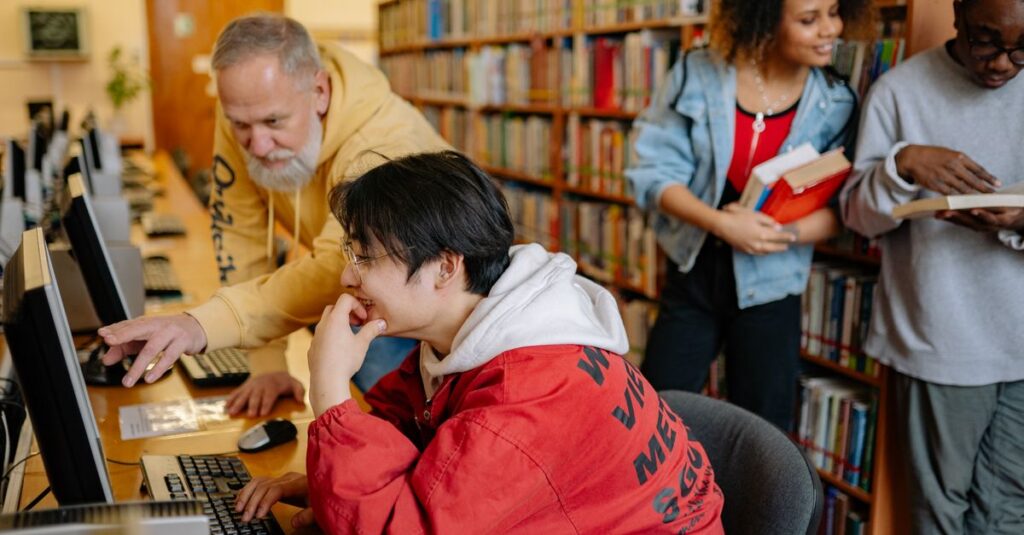 Students collaborating and learning in a library setting, engaging with computers and books.