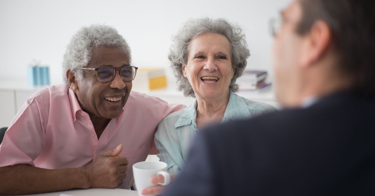 Happy elderly couple enjoying a conversation with a professional advisor indoors.