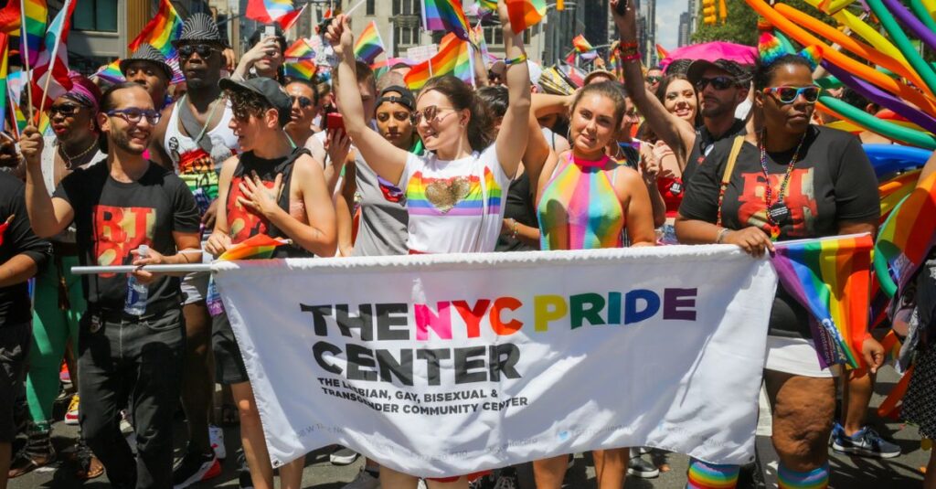 Vibrant scene at the NYC Pride Parade with participants waving rainbow flags.