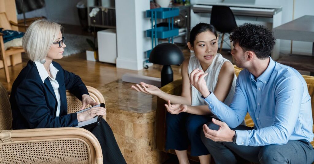 Couple having a discussion with a counselor in a modern living room setting.
