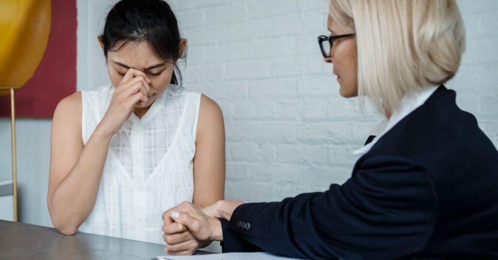 Emotional therapy session featuring a supportive female therapist helping a worried young woman.