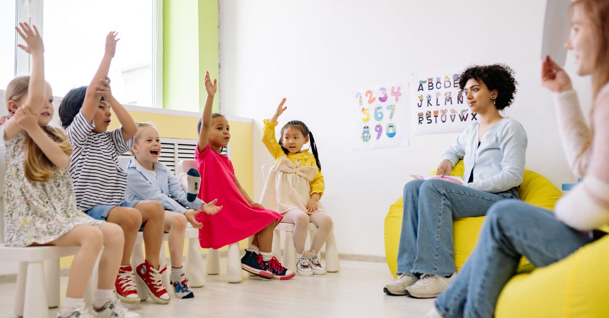Children actively participate in a classroom with teachers, showcasing diversity and engagement.