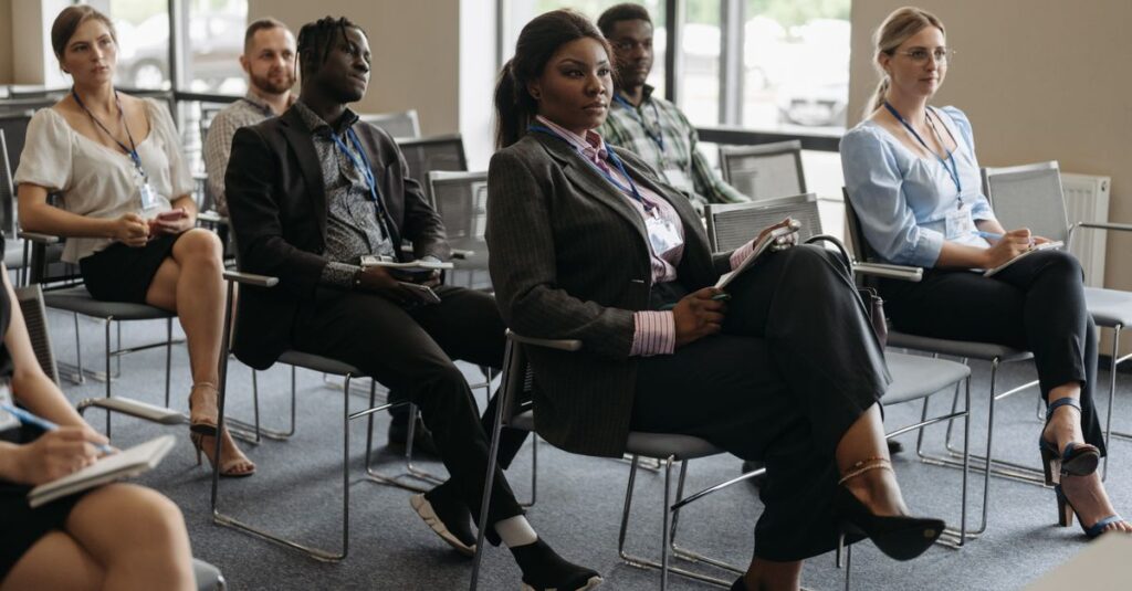 A diverse group of adults attentively listening at a business conference indoors.