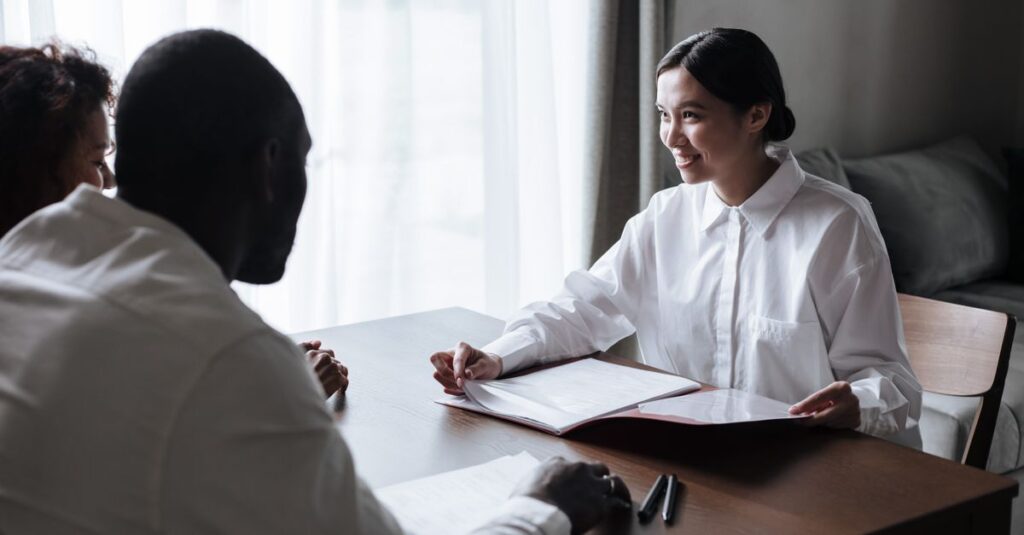 A diverse group discussing documents with a professional in a home interior setting.