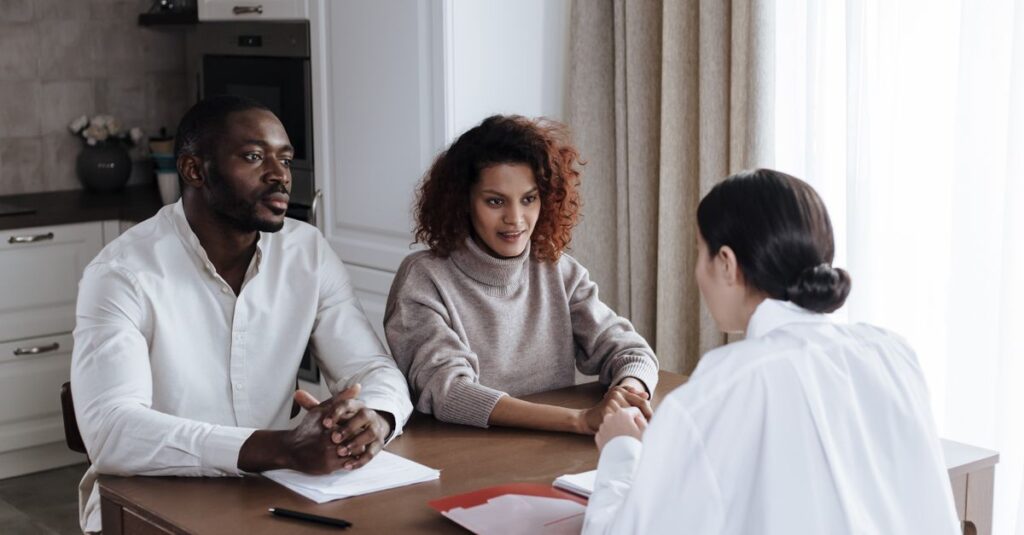 Man and woman discussing documents with a social worker at home.