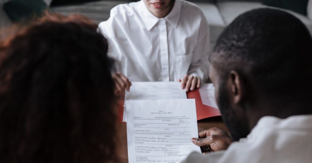 Three people reviewing documents in an office setting, focusing on adoption paperwork.