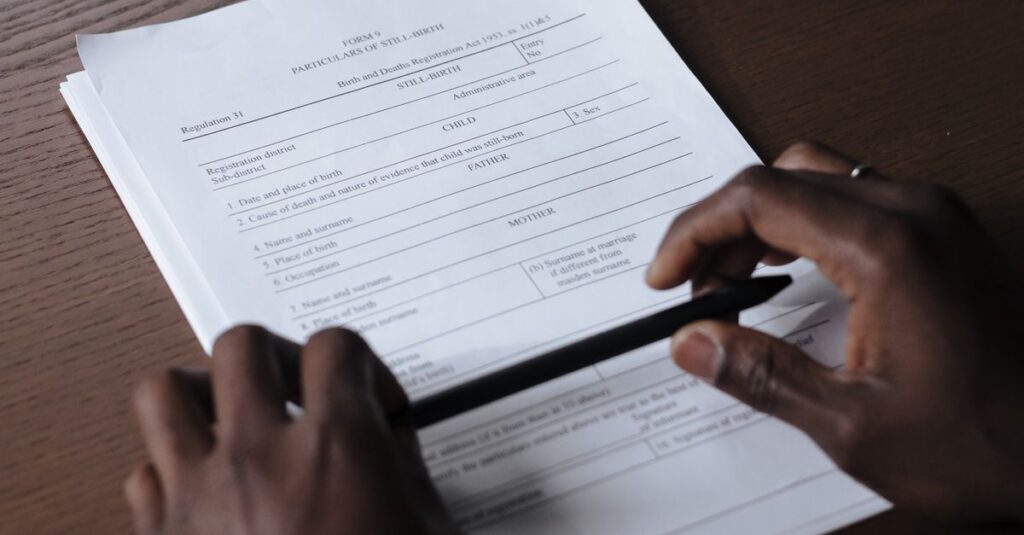 Hands holding a pen and reviewing a contract on a wooden table, creating a professional business setting.